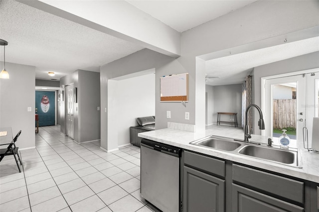 kitchen featuring decorative light fixtures, gray cabinets, light countertops, a sink, and dishwasher