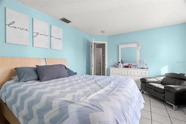 bedroom with light tile patterned floors, visible vents, and a textured ceiling