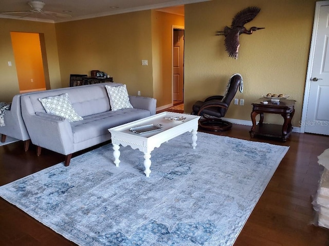 living room featuring dark wood-type flooring, ornamental molding, baseboards, and a ceiling fan