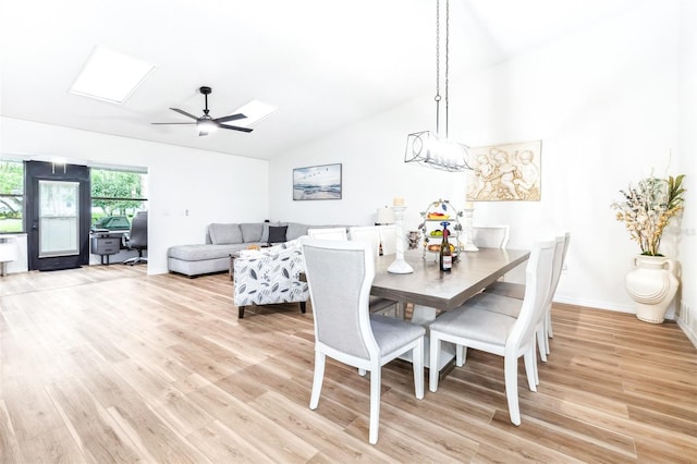 dining area with ceiling fan, light hardwood / wood-style flooring, and lofted ceiling with skylight