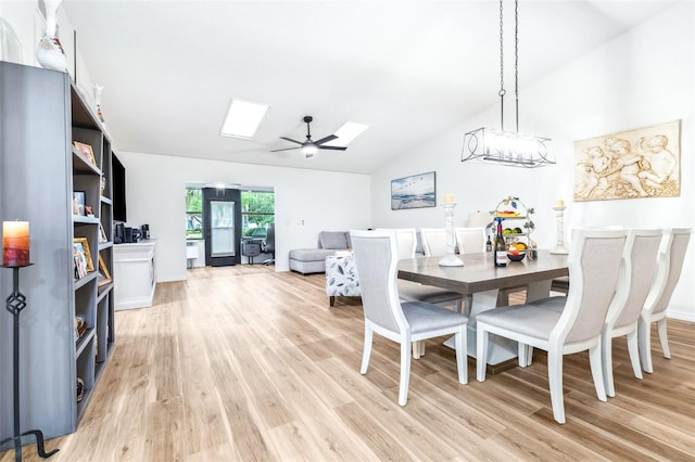 dining room featuring light wood-type flooring, a skylight, high vaulted ceiling, and ceiling fan