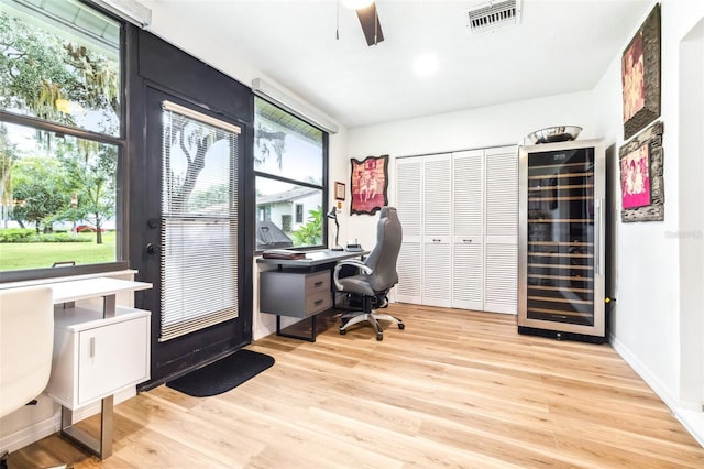 office space with ceiling fan, light hardwood / wood-style flooring, and beverage cooler