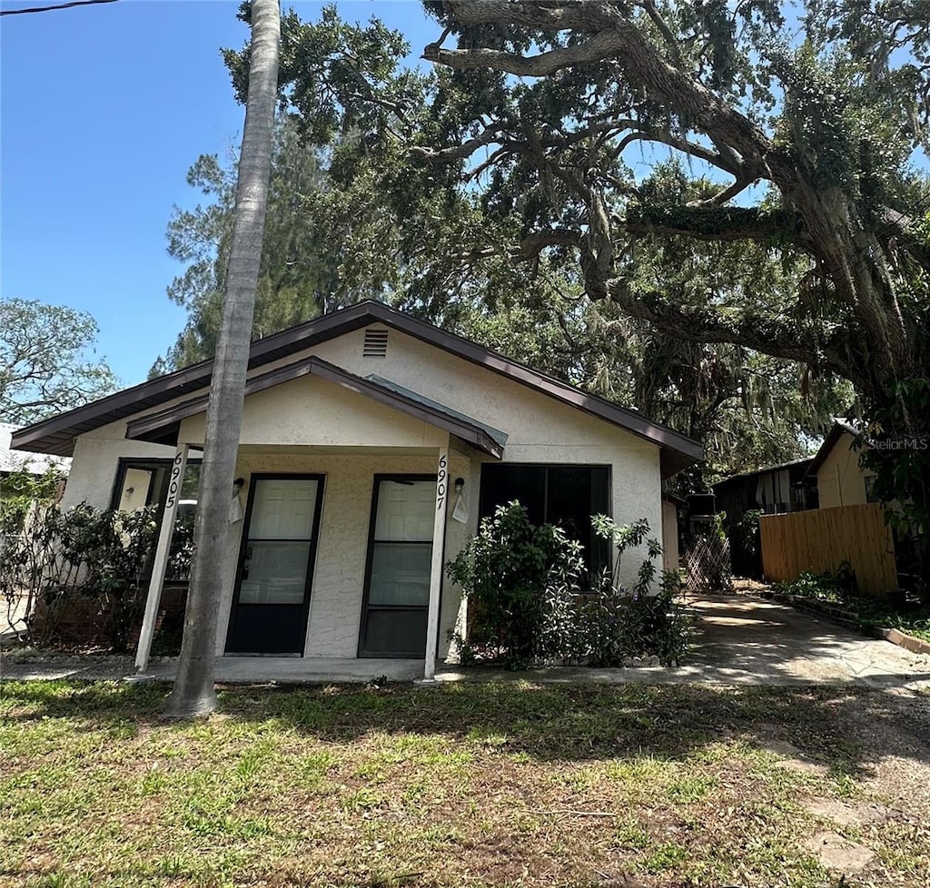 bungalow-style house with a porch, fence, and stucco siding