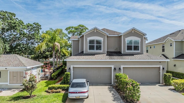 traditional-style home with a shingled roof, concrete driveway, an attached garage, and stucco siding