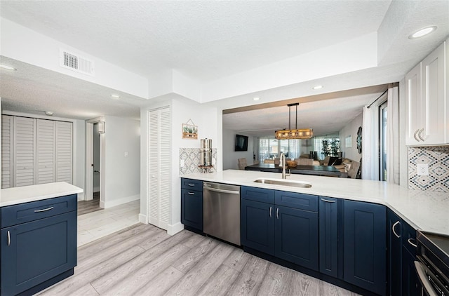 kitchen featuring a sink, blue cabinetry, stainless steel dishwasher, light countertops, and decorative backsplash