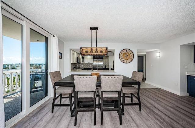 dining space featuring floor to ceiling windows, wood finished floors, baseboards, and a textured ceiling