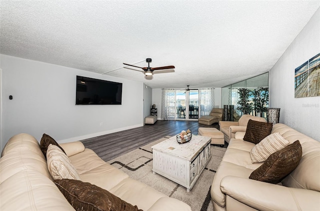 living room featuring a ceiling fan, baseboards, light wood-type flooring, and a textured ceiling