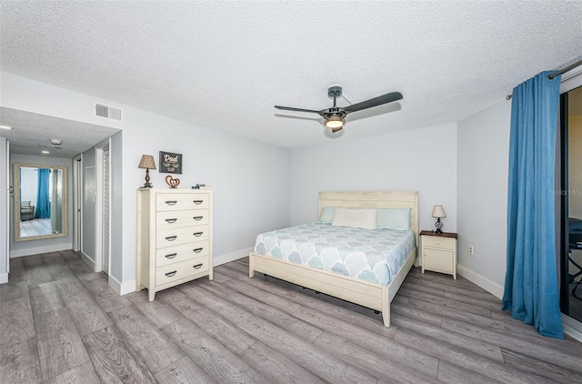 bedroom with baseboards, a textured ceiling, wood finished floors, and a ceiling fan