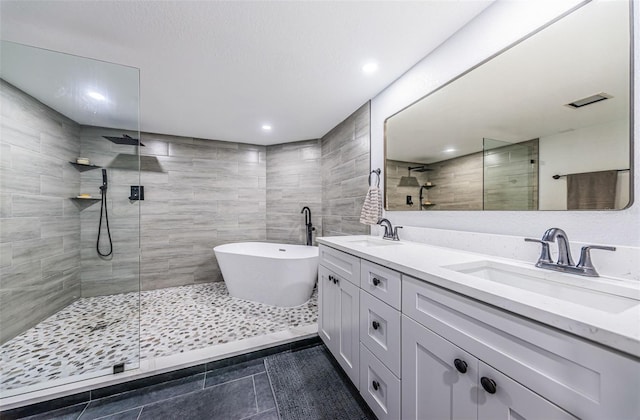 full bathroom featuring a freestanding tub, tiled shower, and a sink