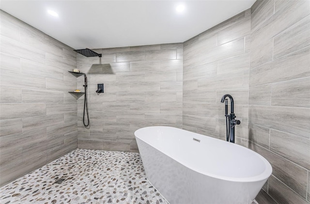 full bath featuring tile walls, a tile shower, and a freestanding bath