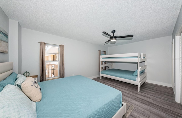 bedroom with a ceiling fan, wood finished floors, baseboards, and a textured ceiling