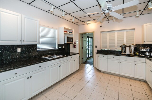 kitchen featuring stainless steel microwave, light tile patterned flooring, and white cabinets