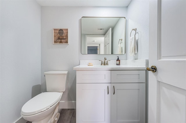 bathroom with visible vents, toilet, wood finished floors, baseboards, and vanity