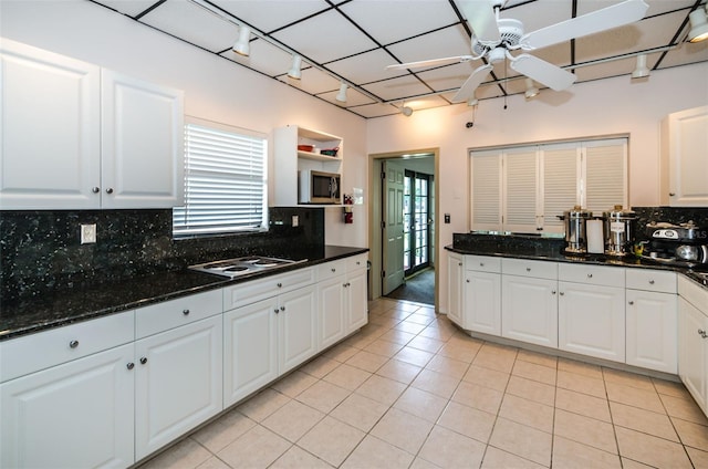 kitchen featuring light tile patterned floors, stainless steel microwave, and white cabinetry