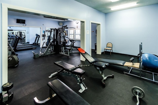 gym featuring a textured ceiling and baseboards