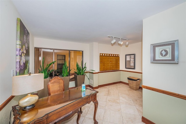 office featuring light tile patterned flooring, mail area, rail lighting, and baseboards