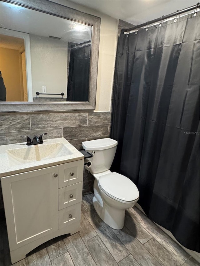 full bathroom featuring toilet, a wainscoted wall, vanity, tile walls, and wood tiled floor