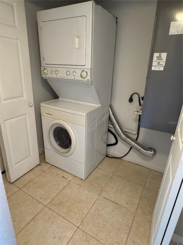 washroom with stacked washing maching and dryer, light tile patterned floors, and laundry area