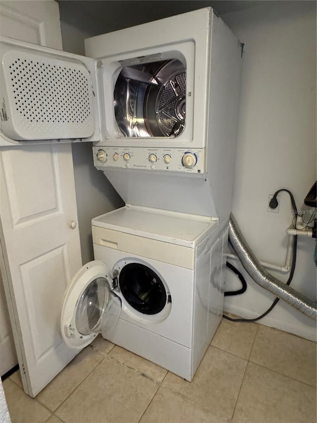 washroom with laundry area, stacked washer / drying machine, and light tile patterned flooring