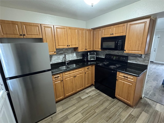 kitchen with black appliances, tasteful backsplash, wood tiled floor, and a sink