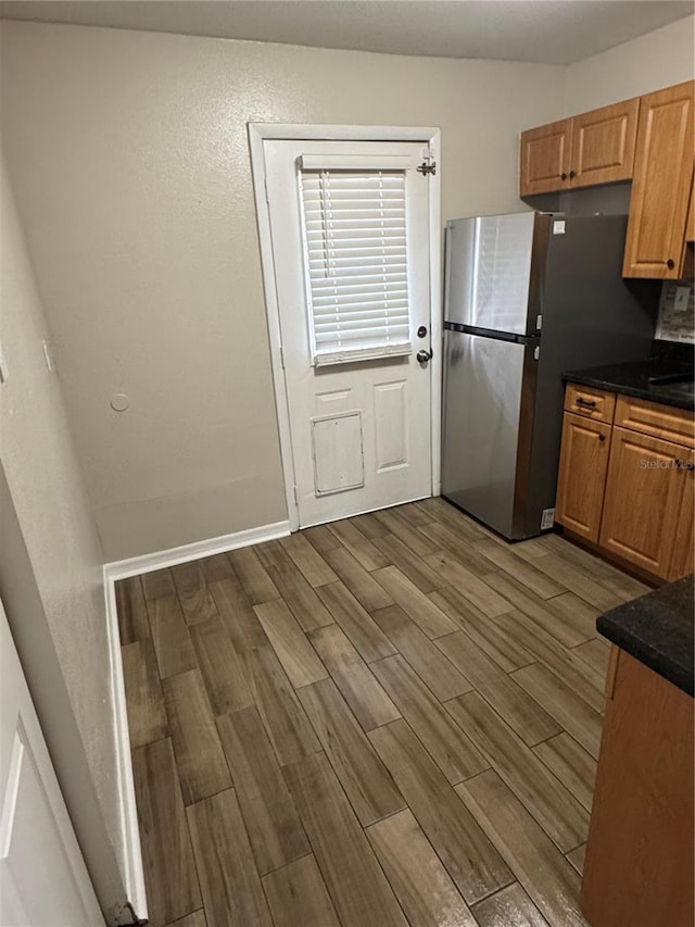 kitchen with freestanding refrigerator, wood finish floors, and dark countertops