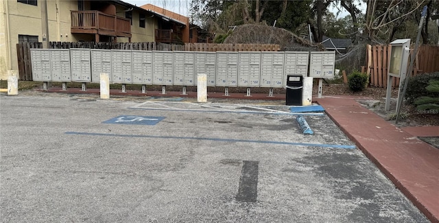 view of community with uncovered parking, fence, and mail area