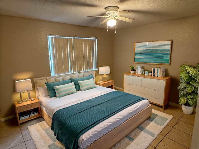 bedroom with light tile patterned floors, ceiling fan, a textured ceiling, and baseboards