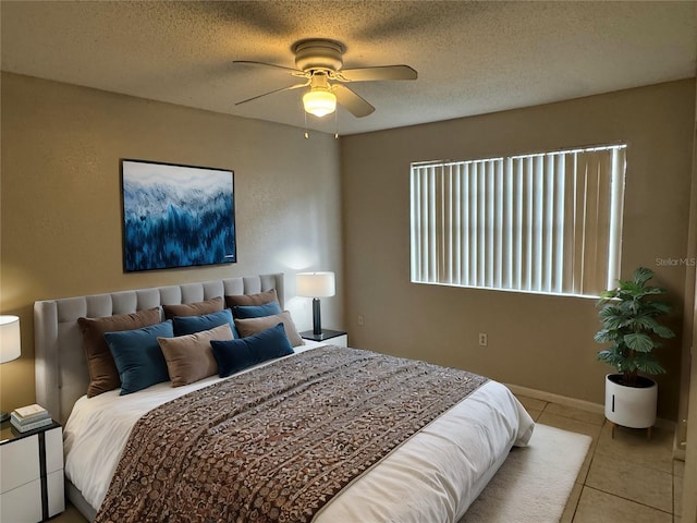 bedroom with a ceiling fan, light tile patterned flooring, a textured ceiling, and baseboards