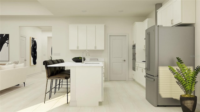 kitchen featuring sink, stainless steel appliances, white cabinets, an island with sink, and a breakfast bar area