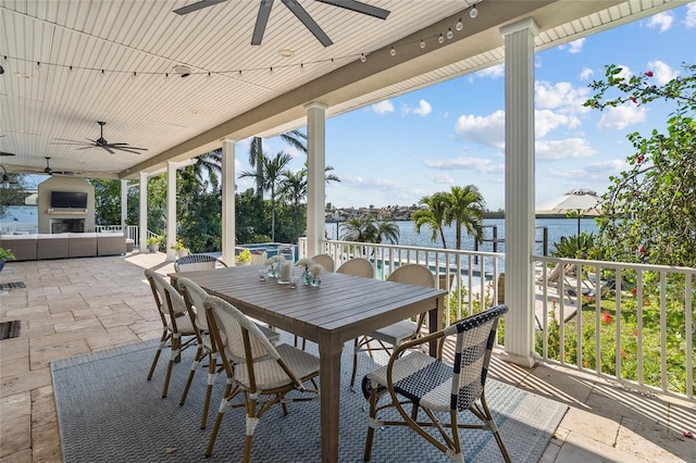 view of patio / terrace with a water view, an outdoor living space with a fireplace, outdoor dining area, and a ceiling fan