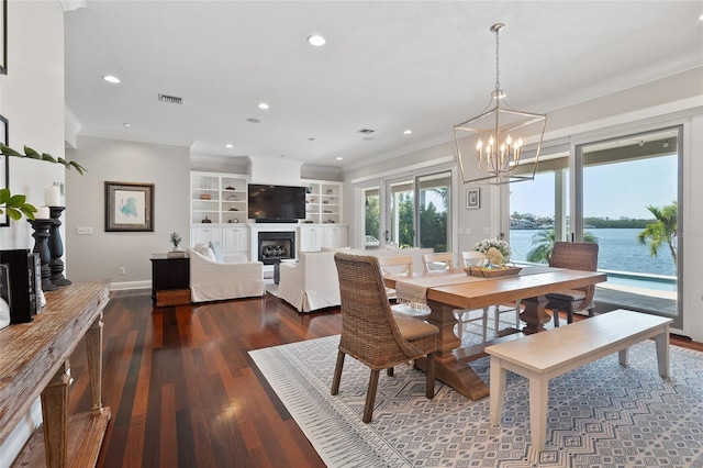 dining space with baseboards, hardwood / wood-style flooring, ornamental molding, a fireplace, and a notable chandelier