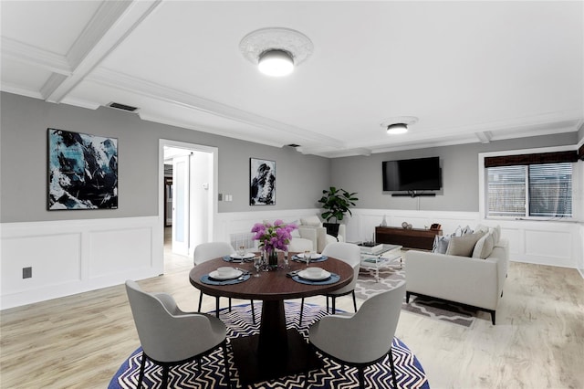 dining space featuring light wood-type flooring, ornamental molding, beamed ceiling, and coffered ceiling