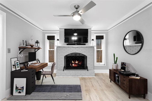 living room with a brick fireplace, crown molding, ceiling fan, and light hardwood / wood-style flooring