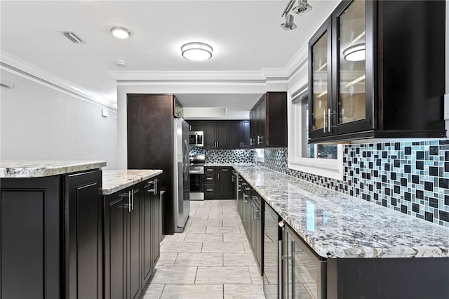 kitchen with beverage cooler, crown molding, stainless steel appliances, and decorative backsplash