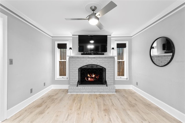 unfurnished living room with ceiling fan, ornamental molding, a brick fireplace, and light hardwood / wood-style flooring