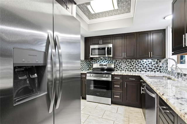 kitchen featuring sink, ornamental molding, backsplash, a raised ceiling, and appliances with stainless steel finishes