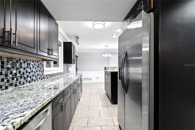 kitchen with ornamental molding, light stone counters, stainless steel fridge, and backsplash