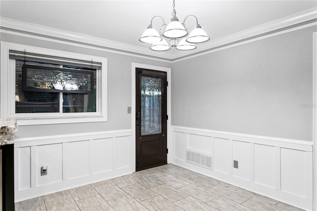 foyer with ornamental molding and an inviting chandelier