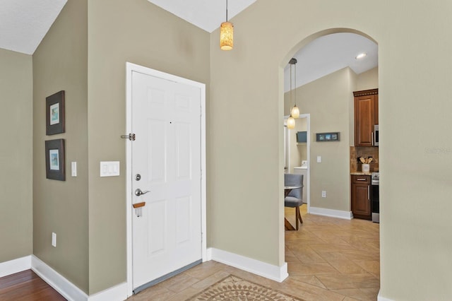 foyer featuring arched walkways and baseboards