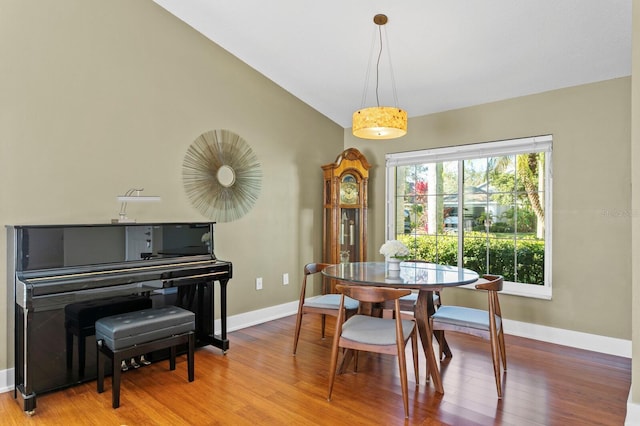 dining space featuring vaulted ceiling, wood finished floors, and baseboards