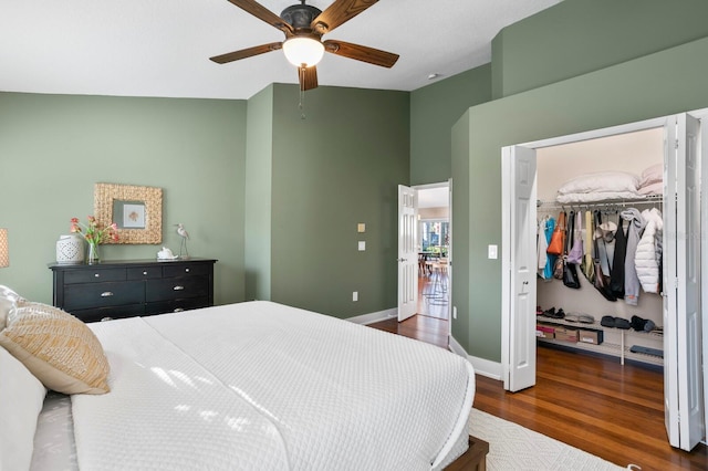 bedroom featuring baseboards, a ceiling fan, dark wood-style flooring, a spacious closet, and a closet