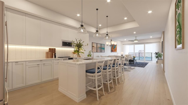 kitchen with a center island, white cabinetry, built in microwave, decorative light fixtures, and light stone countertops