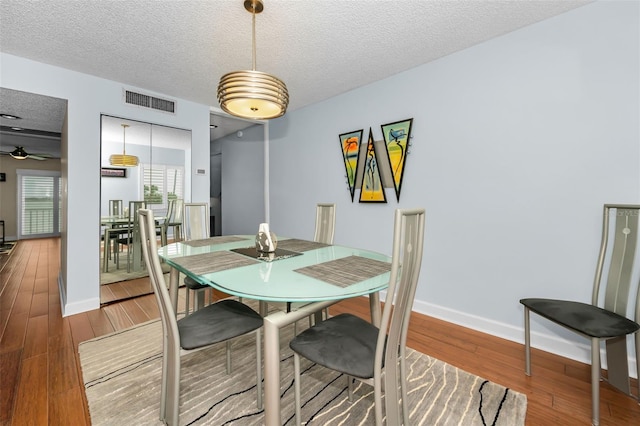 dining area with hardwood / wood-style floors, ceiling fan, and a textured ceiling