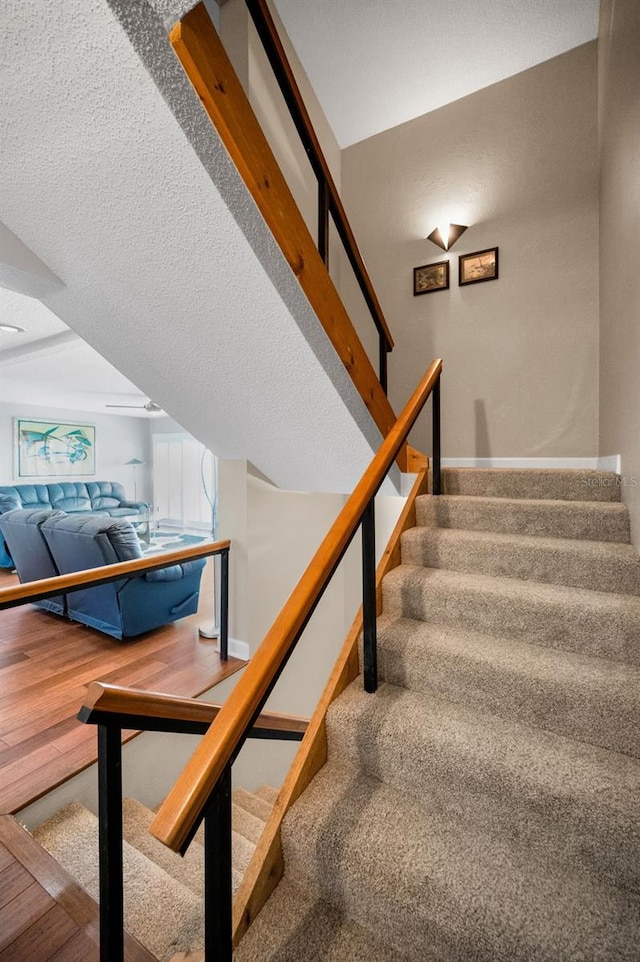 staircase with a textured ceiling and hardwood / wood-style floors