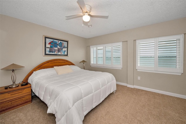 bedroom featuring a textured ceiling, light colored carpet, and ceiling fan