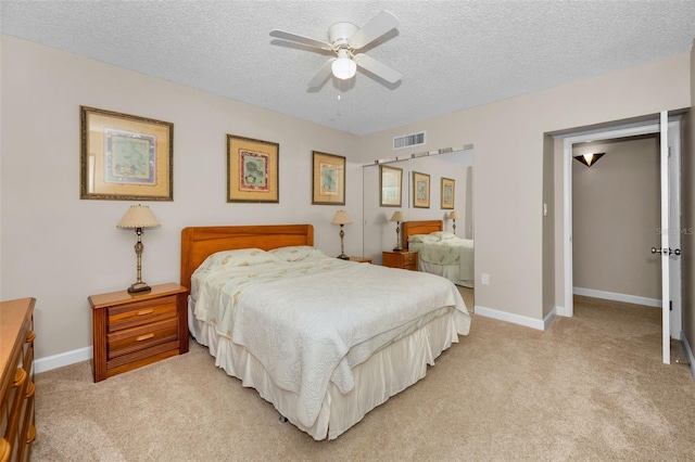 bedroom with a textured ceiling, light carpet, and ceiling fan