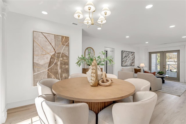 dining room featuring french doors, an inviting chandelier, and light hardwood / wood-style floors