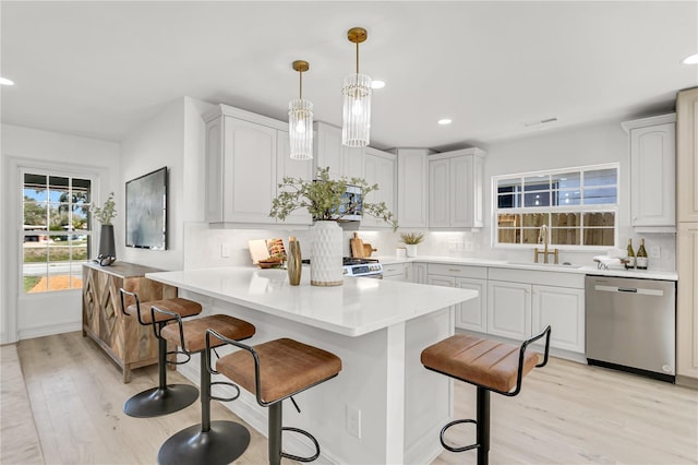 kitchen featuring hanging light fixtures, dishwasher, white cabinets, sink, and kitchen peninsula