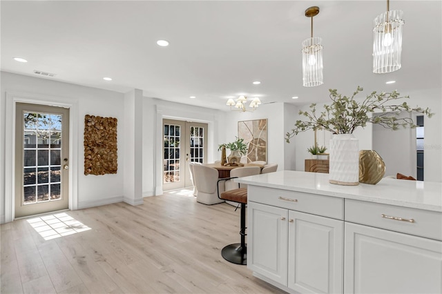 kitchen with light wood-type flooring, white cabinetry, french doors, and light stone counters