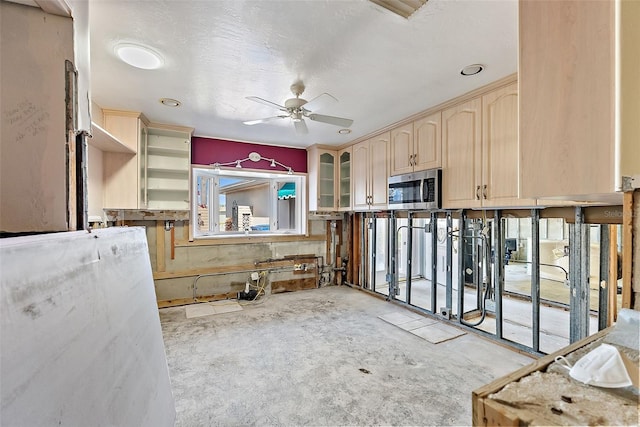 kitchen featuring ceiling fan, light brown cabinetry, and a textured ceiling